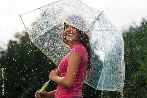 Photo: Young woman standing in summer rain with umbrella Young woman standing in summer rain with umbrella