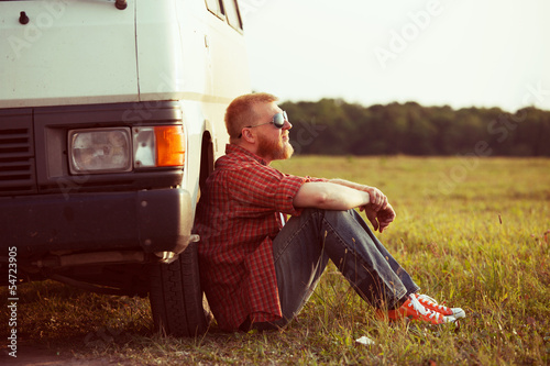 Photo: Driver sits next to his car Driver sits next to his car