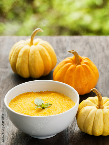 Photo: Pumpkin porridge and pumpkins on black wooden table and natural Pumpkin porridge and pumpkins on black wooden table and natural