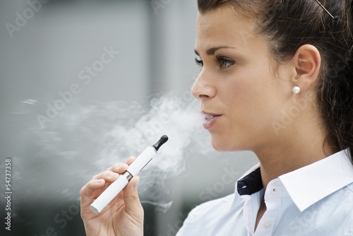 Photo: young woman smoking electronic cigarette outdoor office building young woman smoking electronic cigarette outdoor office building