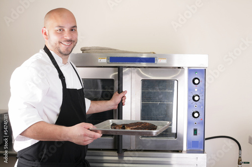Photo: Happy chef taking his freshly baked rib-eye steak Happy chef taking his freshly baked rib-eye steak