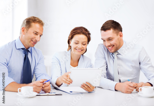 Photo: business team looking at tablet pc in office business team looking at tablet pc in office