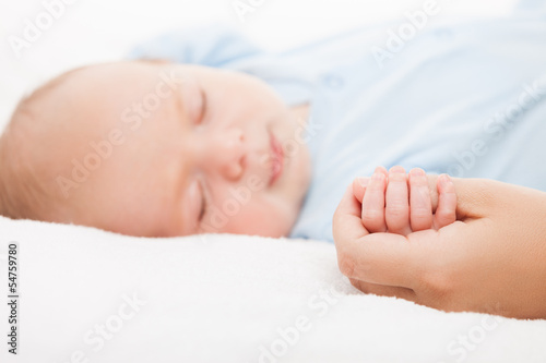 Photo: Cute sleeping newborn baby child holding mother hand Cute sleeping newborn baby child holding mother hand