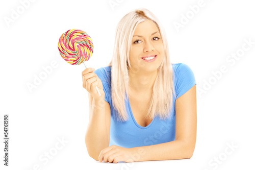 Photo: Blond female lying down with lollipop and looking at camera Blond female lying down with lollipop and looking at camera