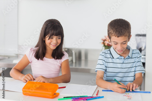 Photo: Smiling siblings drawing in kitchen Smiling siblings drawing in kitchen