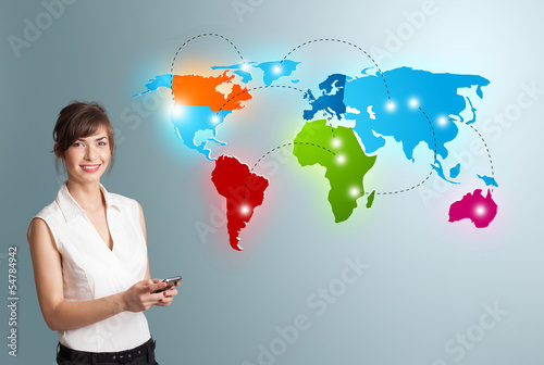 Photo: Young woman holding a phone and presenting colorful world map Young woman holding a phone and presenting colorful world map