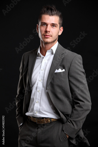 Photo: Handsome young business man standing on black background Handsome young business man standing on black background