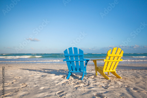 Photo: Beach wooden colorful chairs for vacations on tropical beach in Beach wooden colorful chairs for vacations on tropical beach in