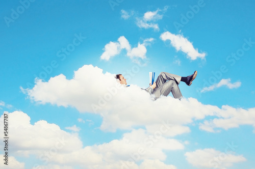 Photo: Businessman lying on clouds Businessman lying on clouds