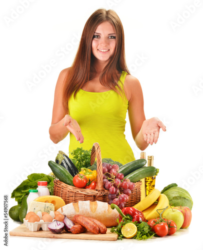 Photo: Young woman with assorted grocery products isolated on white Young woman with assorted grocery products isolated on white