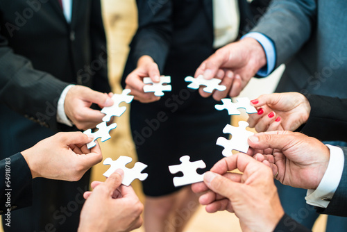 Photo: Teamwork - Business people solving a puzzle Teamwork - Business people solving a puzzle
