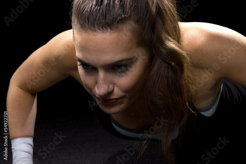 Photo: fit woman doing pushups on black background fit woman doing pushups on black background
