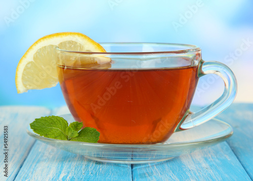 Photo: Cup of tea with lemon on table on blue background Cup of tea with lemon on table on blue background