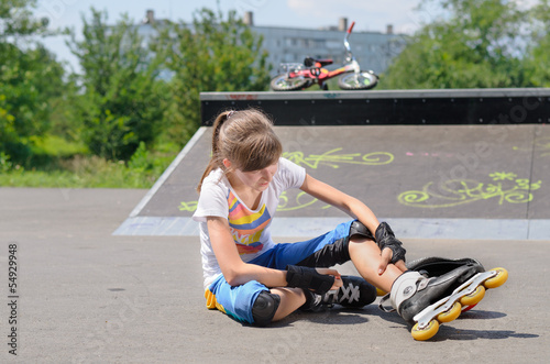 Photo: Young girl wearing rollerblades massaging her calf Young girl wearing rollerblades massaging her calf