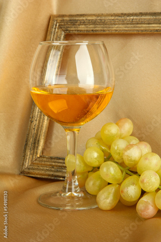 Photo: composition of frame,wine and grapes on bright background composition of frame,wine and grapes on bright background