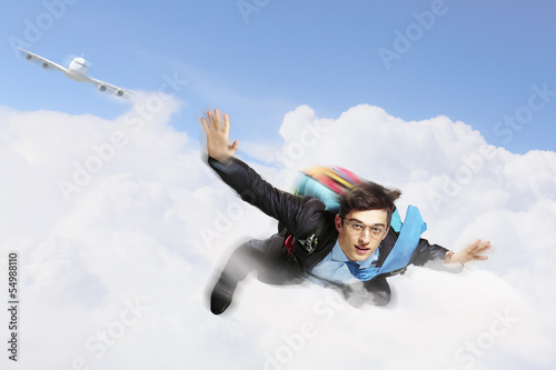 Photo: Young businessman flying with parachute on back Young businessman flying with parachute on back