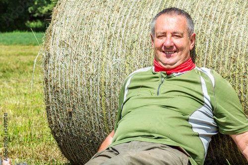 Photo: Organic farmer is resting against the hay bales Organic farmer is resting against the hay bales
