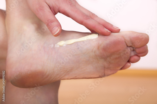 Photo: A woman putting cream on her foot A woman putting cream on her foot