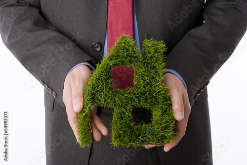 Photo: Person, die Haus-Symbol aus Gras macht Person, die Haus-Symbol aus Gras macht