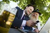Photo: Deutschland, Bayern, Oberbayern, Alter Bayer und junger Geschäftsmann mit Laptop in Biergarten Deutschland, Bayern, Oberbayern, Alter Bayer und junger Geschäftsmann mit Laptop in Biergarten