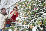 Photo: Österreich, Land Salzburg, Flachau, Junger Mann und Frau schmücken Weihnachtsbaum im Winter Österreich, Land Salzburg, Flachau, Junger Mann und Frau schmücken Weihnachtsbaum im Winter