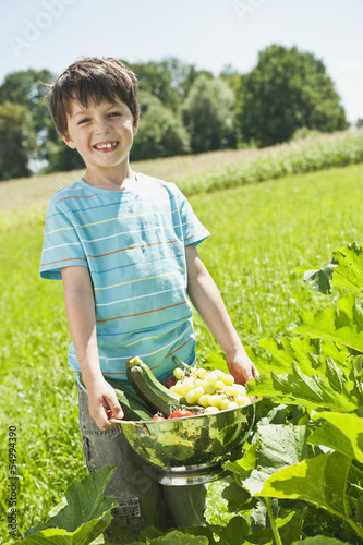 Photo: Deutschland, Bayern, Junge hält Gemüse im Garten, Lächeln Deutschland, Bayern, Junge hält Gemüse im Garten, Lächeln