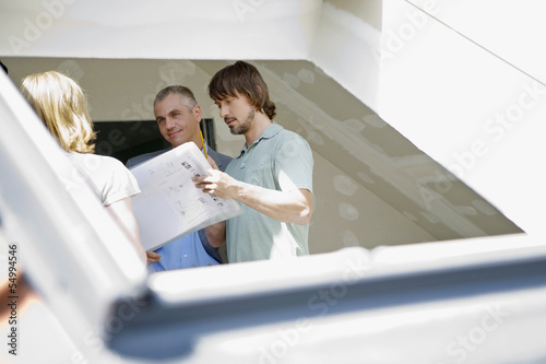 Photo: Junges Paar und Architekt debatieren auf der Baustelle Junges Paar und Architekt debatieren auf der Baustelle