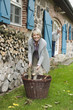 Photo: Deutschland, Kratzeburg, erwachsene Frau mit Brennholz, Senior, Rentner im Hintergrund Deutschland, Kratzeburg, erwachsene Frau mit Brennholz, Senior, Rentner im Hintergrund