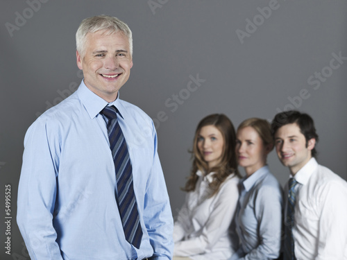 Photo: Ein Mann und zwei Frauen schauen einen Mann an, der lächelt Ein Mann und zwei Frauen schauen einen Mann an, der lächelt