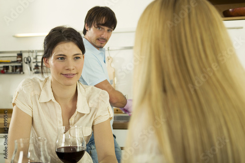 Photo: Drei junge Leute trinken Wein in der Küche Drei junge Leute trinken Wein in der Küche
