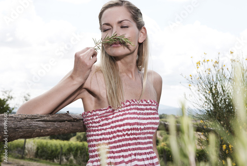 Photo: Italien, Toskana, Magliano, Junge Frau riecht an Rosmarin Italien, Toskana, Magliano, Junge Frau riecht an Rosmarin