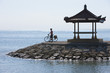 Foto: Indonesien, Bali, Sanur, Mann steht mit dem Fahrrad in der Nähe von Pavillon am Meer Indonesien, Bali, Sanur, Mann steht mit dem Fahrrad in der Nähe von Pavillon am Meer