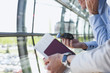 Foto: Deutschland, Leipzig-Halle, Flughafen, Geschäftsmann mit Handy, Person im Vordergrund Deutschland, Leipzig-Halle, Flughafen, Geschäftsmann mit Handy, Person im Vordergrund
