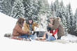 Foto: Österreich, Land Salzburg, Flachau, Junge Männer und Frauen sitzen im Schnee am Kamin Österreich, Land Salzburg, Flachau, Junge Männer und Frauen sitzen im Schnee am Kamin