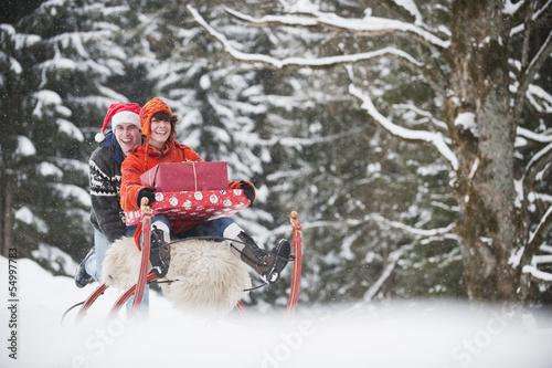 Photo: Österreich, Land Salzburg, Flachau, Junge Frau sitzt auf Schlitten mit Weihnachtsgeschenken Österreich, Land Salzburg, Flachau, Junge Frau sitzt auf Schlitten mit Weihnachtsgeschenken