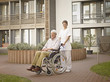 Photo: Deutschland, Köln, Hausmeister schiebt Senior, Rentner im Rollstuhl außerhalb Pflegeheim Deutschland, Köln, Hausmeister schiebt Senior, Rentner im Rollstuhl außerhalb Pflegeheim