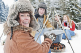 Foto: Österreich, Land Salzburg, Flachau, Junge Männer und Frauen sitzen im Schnee am Kamin Österreich, Land Salzburg, Flachau, Junge Männer und Frauen sitzen im Schnee am Kamin