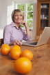 Photo: Deutschland, Kratzeburg, erwachsene Frau mit Laptop, Früchte auf dem Tisch im Vordergrund Deutschland, Kratzeburg, erwachsene Frau mit Laptop, Früchte auf dem Tisch im Vordergrund