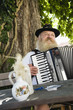 Photo: Deutschland, Bayern, Oberbayern, erwachsener Mann in traditioneller Tracht spielt Akkordeon in Biergarten Deutschland, Bayern, Oberbayern, erwachsener Mann in traditioneller Tracht spielt Akkordeon in Biergarten