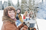 Foto: Österreich, Land Salzburg, Flachau, Junge Männer und Frauen sitzen im Schnee am Kamin Österreich, Land Salzburg, Flachau, Junge Männer und Frauen sitzen im Schnee am Kamin