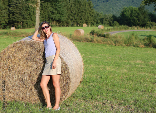 Photo: Young pregnant woman standing next to hay bale Young pregnant woman standing next to hay bale