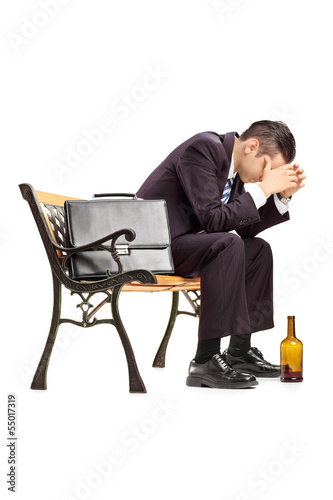 Photo: Disappointed young businessperson sitting on a wooden bench Disappointed young businessperson sitting on a wooden bench