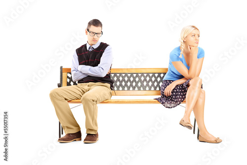 Photo: Young couple sitting on a wooden bench after having an argument Young couple sitting on a wooden bench after having an argument