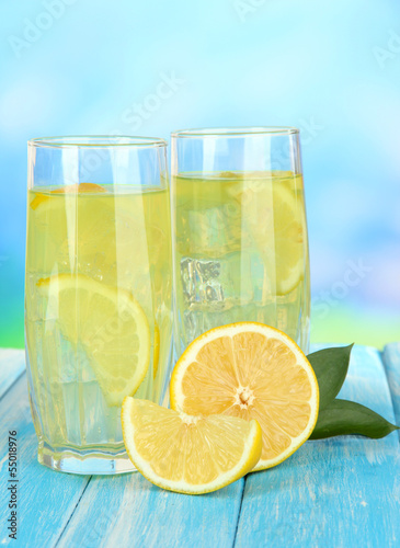 Photo: Delicious lemonade on table on blue background Delicious lemonade on table on blue background
