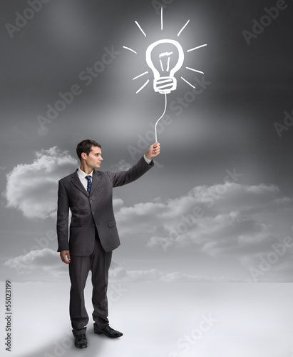 Photo: Businessman holding a drawing of a light bulb Businessman holding a drawing of a light bulb
