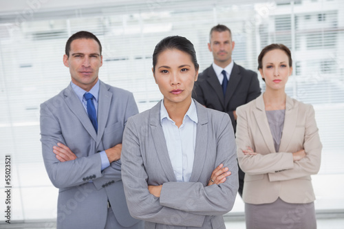 Photo: Serious work team posing crossing arms Serious work team posing crossing arms