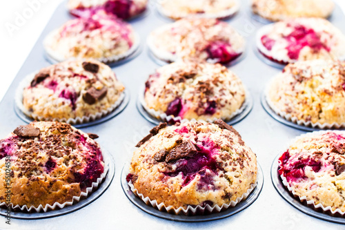 Photo: Homemade chocolate small cakes with cherry in baking tray. Clos Homemade chocolate small cakes with cherry in baking tray. Clos