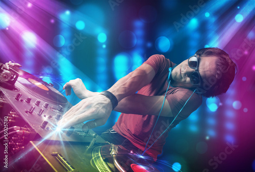Photo: Dj mixing music in a club with blue and purple lights Dj mixing music in a club with blue and purple lights