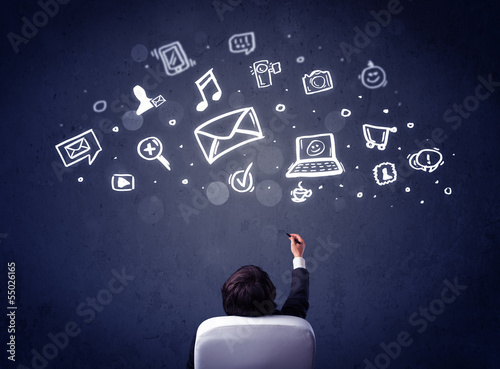 Photo: Businessman in chair with multimedia icons over his head Businessman in chair with multimedia icons over his head