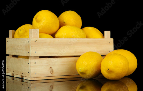 Photo: Ripe lemons in wooden box isolated on black Ripe lemons in wooden box isolated on black